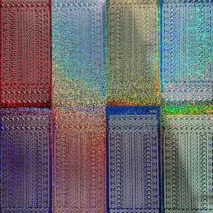 May include: A selection of decorative sticker sheets in colours such as red, blue, and gold. Each sheet has a repeating pattern of vertical lines and decorative borders, with a shimmering, holographic effect.