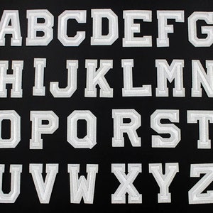 May include: A full alphabet of white, embroidered varsity letter patches, each with a layered design, set against a black background. Ideal for customising clothing or accessories.