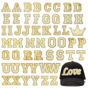 May include: A selection of gold sequined alphabet letters and a gold sequined crown. A black baseball cap with the word "Love" in gold sequined letters is also included. The letters are in a serif font and are arranged on a white background.
