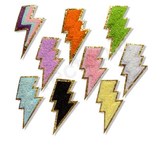 May include: Eight colourful lightning bolt patches. Each bolt has a textured fabric in shades of purple, pink, orange, green, blue, black, white, and yellow, with a gold glitter outline. These patches are perfect for adding flair to clothing or accessories.