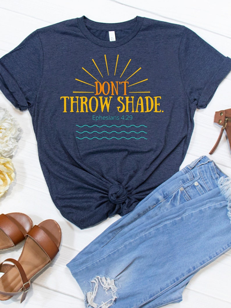 May include: A navy blue t-shirt with a sunburst design and the text "DON'T THROW SHADE."  The text "Ephesians 4:29" is below the main text.