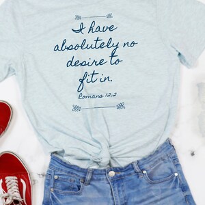 May include: A light blue t-shirt with the text "I have absolutely no desire to fit in. Romans 12:2" printed in dark blue.