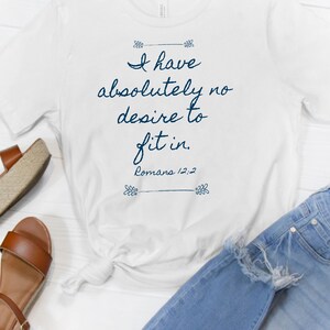 May include: White t-shirt with a blue graphic that says "I have absolutely no desire to fit in. Romans 12:2"