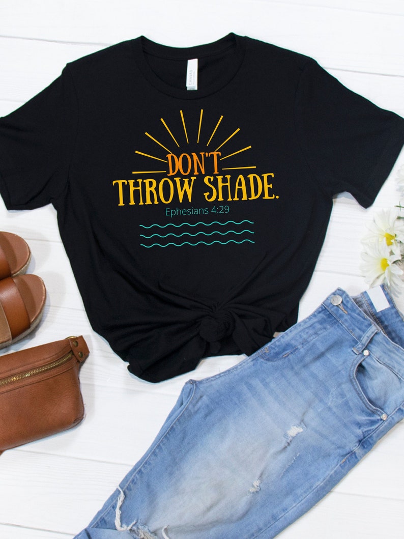 May include: Black t-shirt with the text "Don't Throw Shade." in orange and yellow with a sun graphic. The text "Ephesians 4:29" is below the graphic.