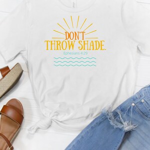 May include: White t-shirt with a yellow sun graphic and the text "Don't Throw Shade. Ephesians 4:29".
