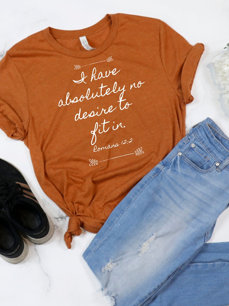 May include: A rust-coloured t-shirt with the text "I have absolutely no desire to fit in. Romans 12:2" printed in white.