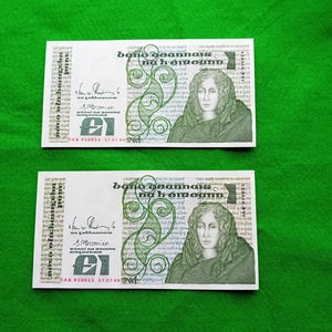 May include: Two Irish banknotes, each with a portrait of a woman and green decorative elements. The text "bano beannais na h-éireann" is visible. The banknotes are set against a green backdrop.