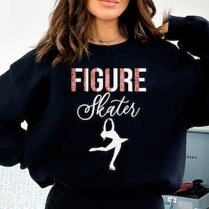 May include: Black sweatshirt with the text "FIGURE Skater" in white and pink glitter lettering. A white silhouette of a figure skater is below the text.