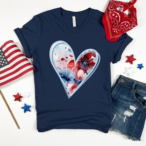 May include: A navy blue t-shirt with a white outline heart design featuring red, white, and blue watercolor flowers.