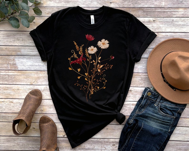 May include: Black t-shirt with a floral print featuring red, white and brown flowers and leaves.