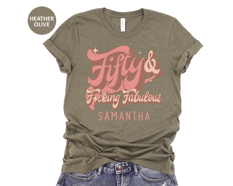 May include: A heather olive t-shirt with a pink graphic that says "Fifty & F*cking Fabulous" with the name Samantha below it.