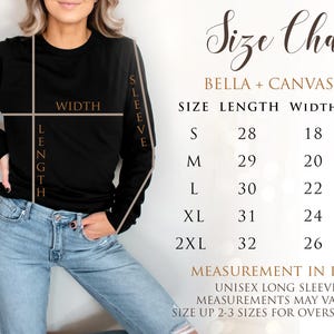 Op de afbeelding: Een zwart shirt met lange mouwen met een maattabel. De tabel geeft de afmetingen in inches voor een unisex shirt met lange mouwen, inclusief lengte, breedte en mouwafmetingen voor de maten S tot 2XL. Het shirt is Bella + Canvas 3501.