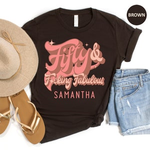May include: A brown t-shirt with the text "Fifty & F*cking Fabulous" in pink lettering. The name "Samantha" is printed below the text.