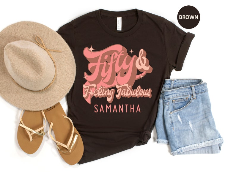 May include: A brown t-shirt with the text "Fifty & F*cking Fabulous" in pink lettering. The name "Samantha" is printed below the text.