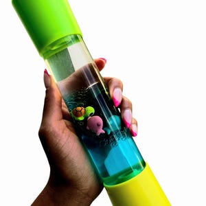 May include: A clear, cylindrical sensory toy with a green and yellow cap and base. The tube contains blue liquid and small, colorful sea creature figurines. The toy is held at an angle against a white background.