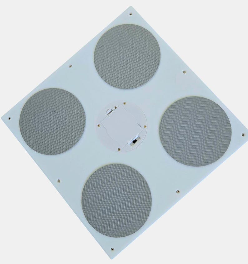 Może przedstawiać: Biała kwadratowa mata do tańca z czterema szarymi okrągłymi podkładkami. Mata ma komorę baterii na g&oacute;rze.