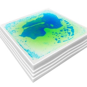 Może przedstawiać: Kwadratowa zabawka sensoryczna z białą ramką i przezroczystym płynem w środku. Płyn jest mieszanką kolor&oacute;w niebieskiego i zielonego i zawiera bąbelki.