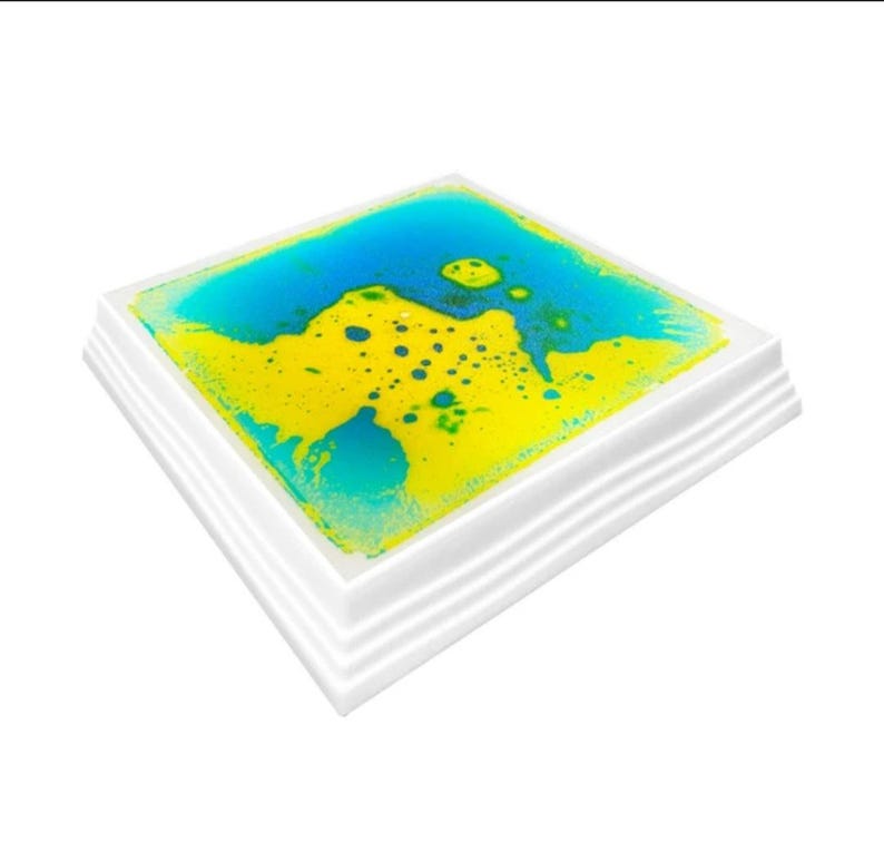 Może przedstawiać: Kwadratowa zabawka sensoryczna z białą ramką i niebieskim i ż&oacute;łtym płynem w środku. Płyn porusza się i tworzy wzory.
