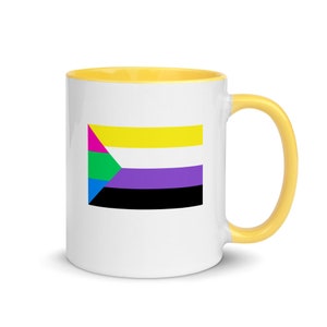 Puede incluir: Una taza de cerámica blanca con un borde y un asa amarillos. La taza presenta una bandera del orgullo multicolor con un diseño amarillo, morado, negro, verde, azul y rosa.