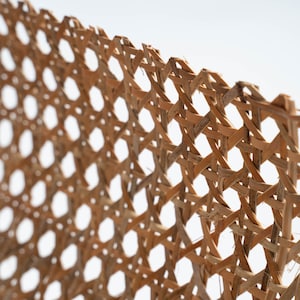 Pode incluir: Um close-up de uma cesta de vime tecida, mostrando o padr&atilde;o intrincado das mechas tecidas. A cesta &eacute; feita de materiais naturais e tem uma cor castanho claro.