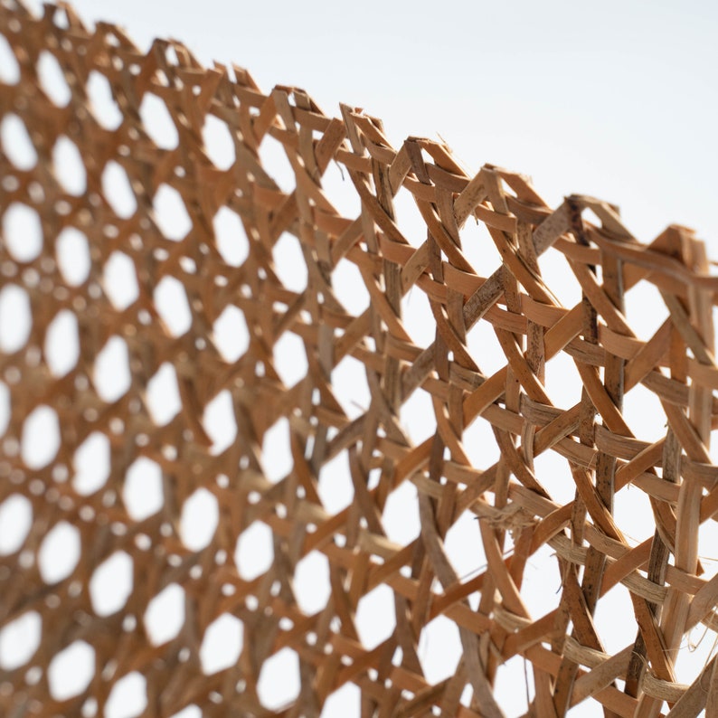 Pode incluir: Um close-up de uma cesta de vime tecida, mostrando o padr&atilde;o intrincado das mechas tecidas. A cesta &eacute; feita de materiais naturais e tem uma cor castanho claro.