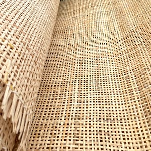 May include: Close-up of a woven cane webbing material, often used for chair seats and backs. The material is light brown and has a tight weave.