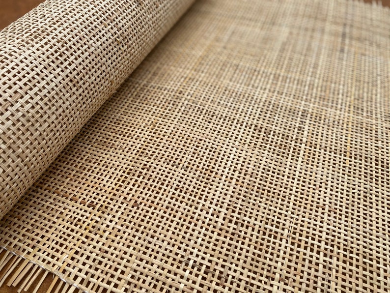 May include: A close-up of a roll of natural cane webbing, a woven material often used for upholstery and furniture making. The webbing is light brown and has a tight weave.