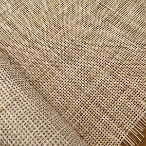 May include: A roll of natural woven cane webbing, a material used for chair seats and other furniture upholstery. The webbing is made of a tightly woven, natural material with a light brown color.