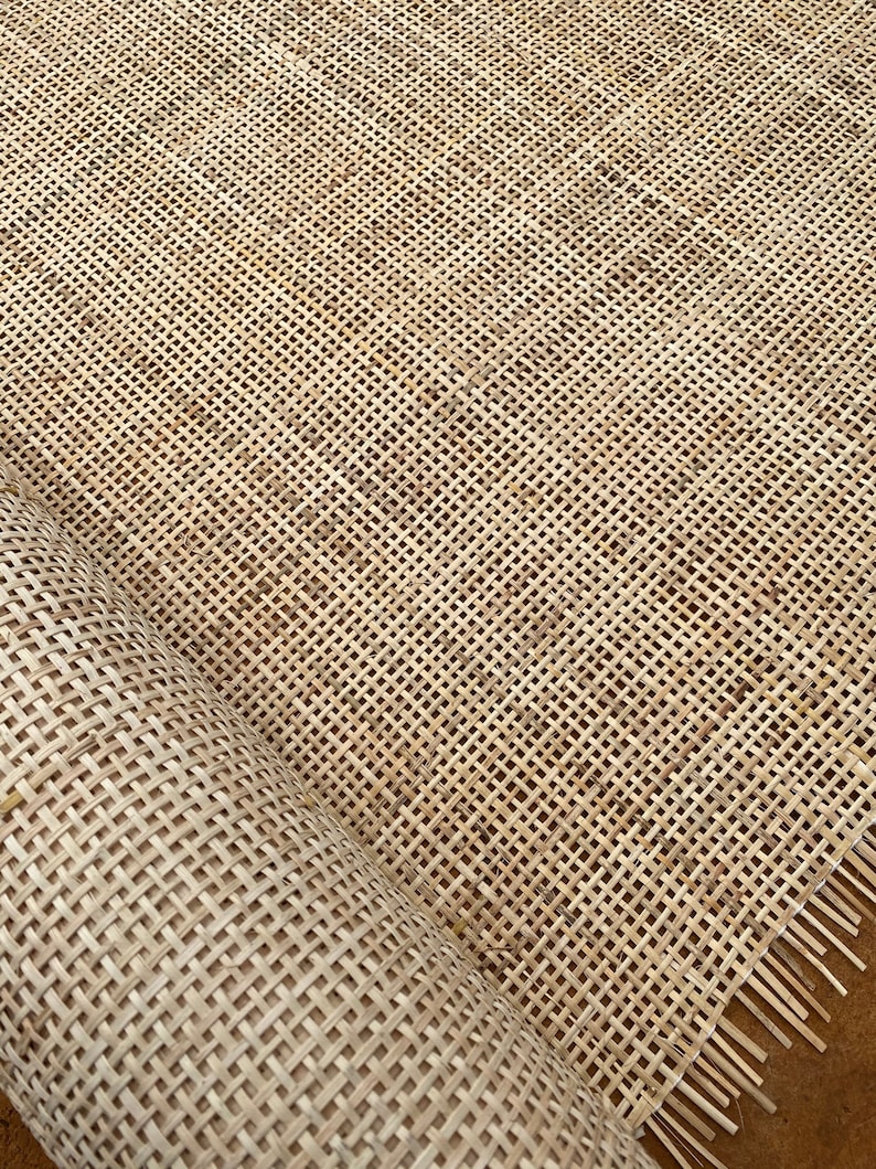 May include: A roll of natural woven cane webbing, a material used for chair seats and other furniture upholstery. The webbing is made of a tightly woven, natural material with a light brown color.