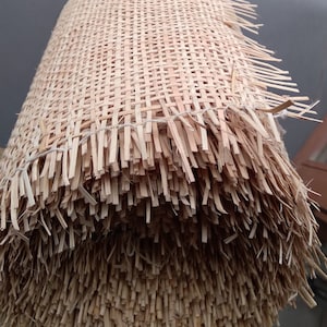 May include: A roll of natural woven cane webbing, a material used for chair seats and other furniture upholstery. The cane is woven into a tight, even grid pattern.