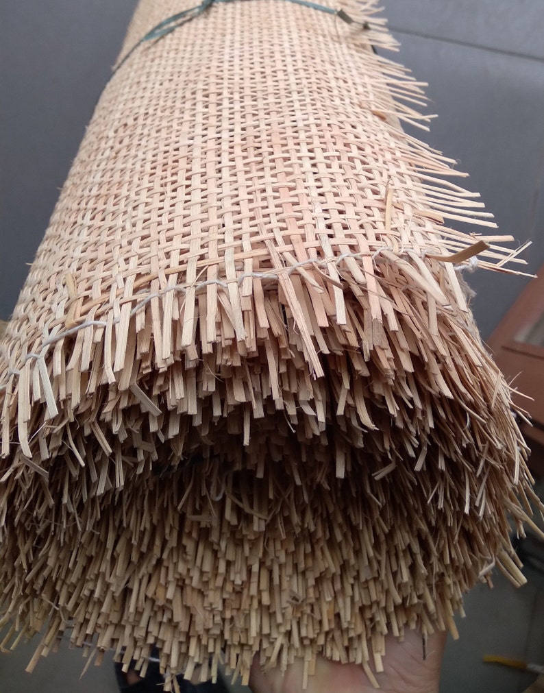 May include: A roll of natural woven cane webbing, a material used for chair seats and other furniture upholstery. The cane is woven into a tight, even grid pattern.