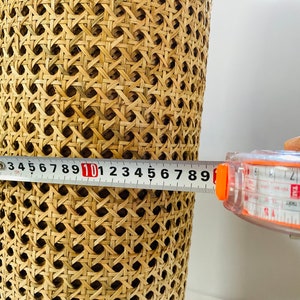 Pode incluir: Um close-up de um material de vime tecido sendo medido com uma fita m&eacute;trica. A fita m&eacute;trica l&ecirc; 10 polegadas.