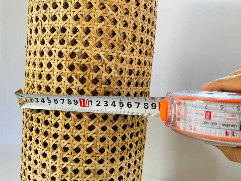Pode incluir: Um close-up de um material de vime tecido sendo medido com uma fita m&eacute;trica. A fita m&eacute;trica l&ecirc; 10 polegadas.