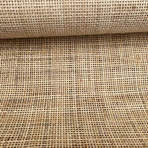 May include: A close-up of a woven cane material, often used for chair seats and other furniture. The material is light brown and has a natural, rustic look.