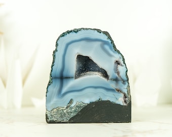 May include: A blue agate geode with a natural crystal formation. The geode has a smooth, polished exterior and a rough, textured interior. The geode is a beautiful example of natural beauty.