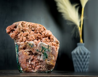 Könnte beinhalten: Ein großer, rosafarbener und grüner Geode mit einer rauen, strukturierten Oberfläche. Der Geode ist mit kleinen, rosafarbenen Kristallen gefüllt.