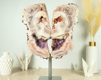 May include: A large, natural amethyst geode with a pink and purple color scheme. The geode is split in half and mounted on a metal stand. The geode has a natural, rough texture and is a beautiful example of a natural crystal formation.