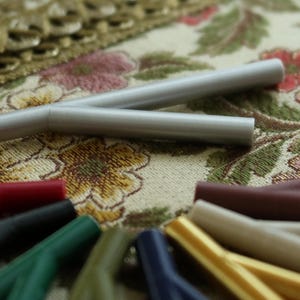 Pode incluir: Um conector em Y prateado com uma variedade de cabos coloridos presos a ele. O conector está sobre um tecido com padrão floral.