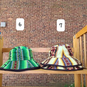 K&ouml;nnte beinhalten: Zwei Bucket-Hats mit bunten geometrischen Mustern. Der Hut links ist gr&uuml;n mit schwarzem Besatz und der Hut rechts ist cremefarben mit schwarzem, rotem und blauem Besatz.