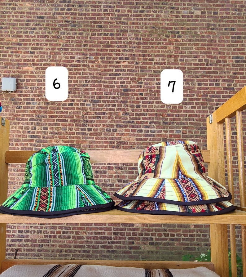 K&ouml;nnte beinhalten: Zwei Bucket-Hats mit bunten geometrischen Mustern. Der Hut links ist gr&uuml;n mit schwarzem Besatz und der Hut rechts ist cremefarben mit schwarzem, rotem und blauem Besatz.