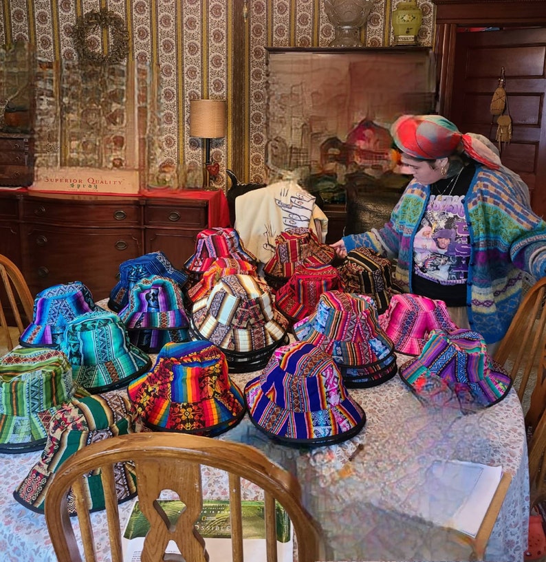 K&ouml;nnte beinhalten: Eine Sammlung bunter, gemusterter Bucket-Hats mit verschiedenen Designs. Die H&uuml;te sind auf einem Tisch mit einer wei&szlig;en Tischdecke angeordnet.