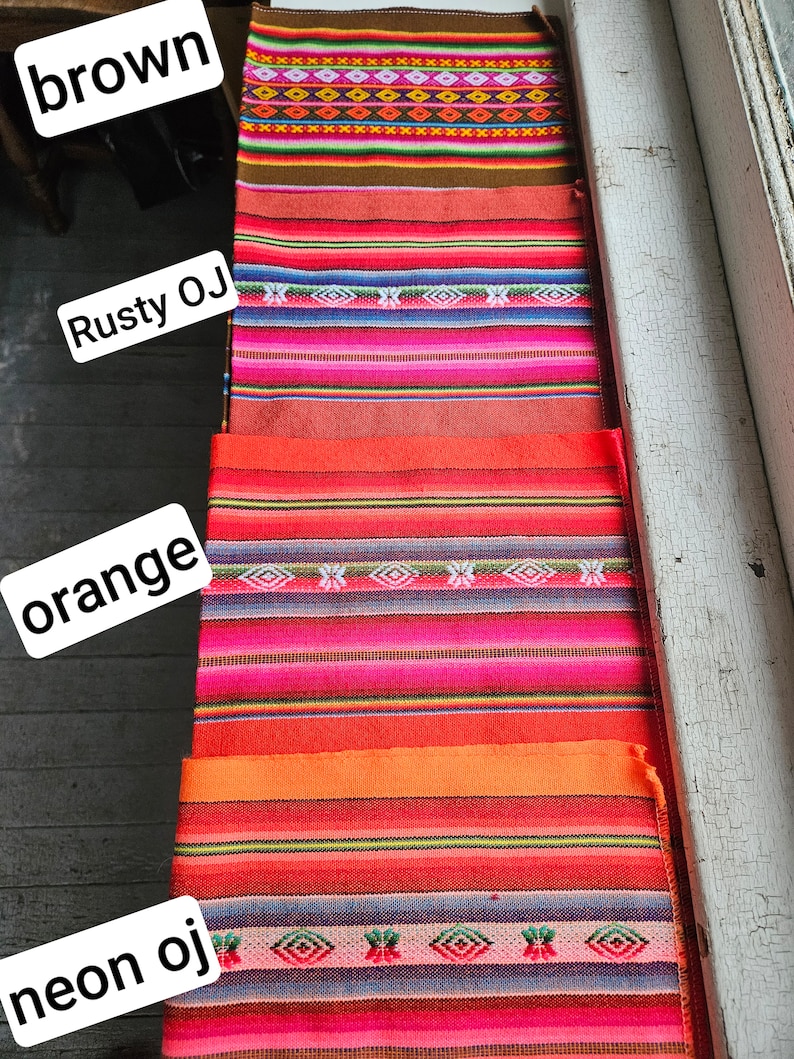 May include: A close-up of five colorful woven fabric samples. The samples are arranged vertically, with the top sample being brown, followed by rusty orange, orange, and neon orange. The bottom sample is a vibrant pink with a blue and green pattern.