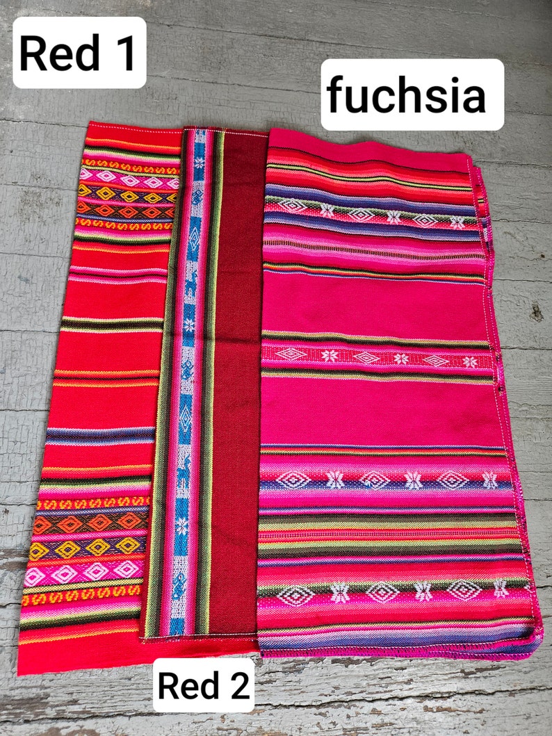 May include: Three woven fabric strips, one red, one red with a blue and white pattern, and one fuchsia with a multi-colored pattern. The strips are labeled "Red 1", "Red 2", and "fuchsia".