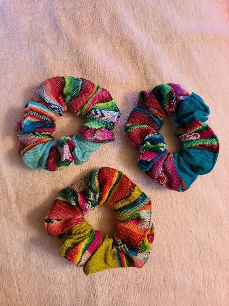 May include: Three colorful scrunchies with a woven pattern. The scrunchies are made of fabric and have a variety of colors, including pink, green, blue, yellow, and red.