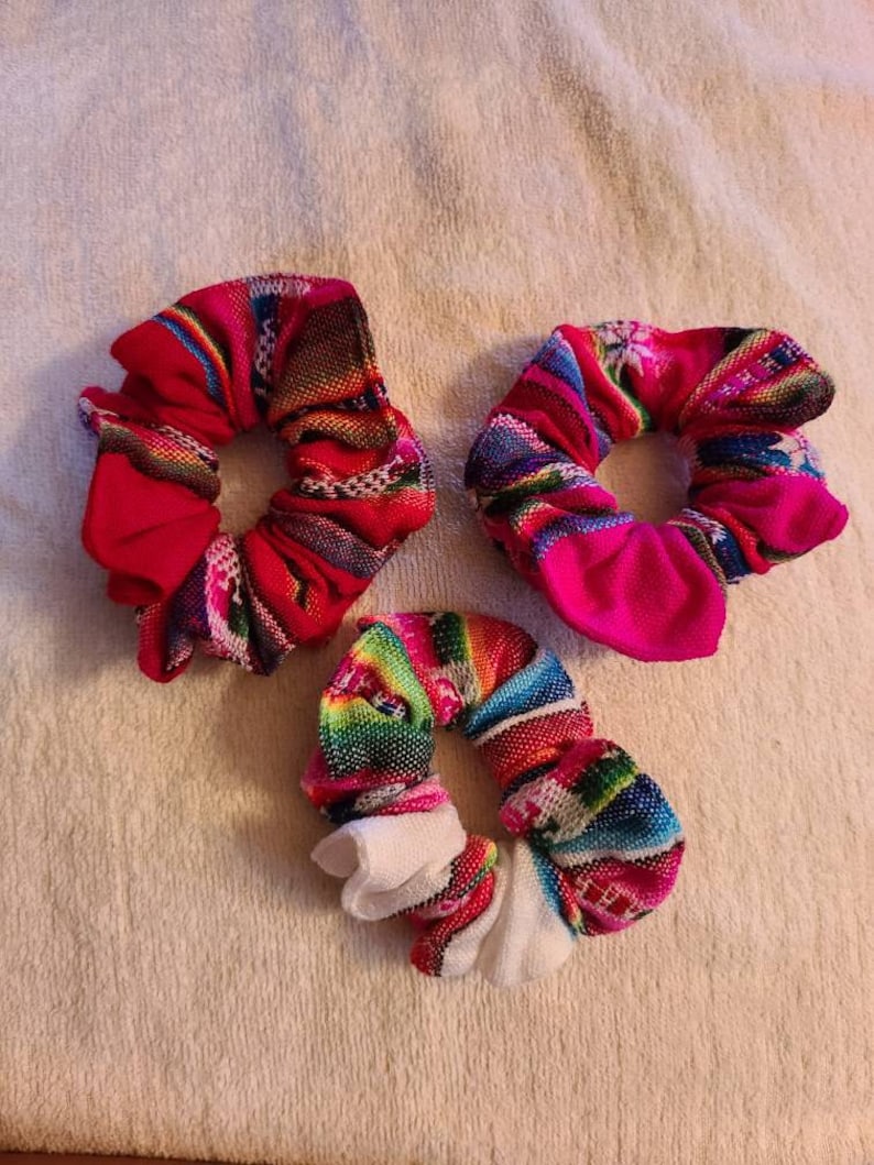 May include: Three colorful scrunchies with a variety of patterns. The scrunchies are made of fabric and have a gathered look.