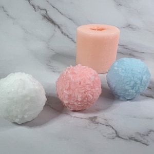 Peut inclure: Quatre bougies rondes, une rose, une blanche, une bleue et une pêche, avec une surface texturée. Les bougies sont disposées en rangée sur une surface en marbre blanc.