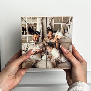 May include: A wooden photo cube with six sides, each displaying a different image of a family with two small white rabbits. The family are sitting on a sofa, smiling and holding the rabbits.
