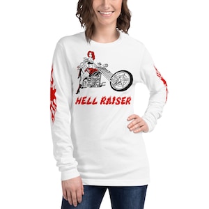 May include: White long-sleeve t-shirt with a black and white illustration of a woman on a motorcycle. The text "HELL RAISER" is printed in red below the illustration. The sleeves have red flame designs.
