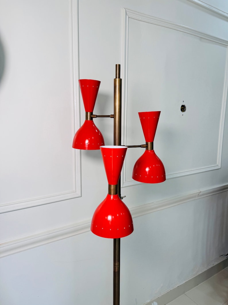 May include: A red and brass floor lamp with three adjustable shades. The lamp has a mid-century modern design.