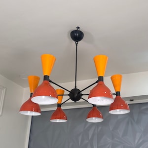 May include: A black metal chandelier with six orange and red glass shades. The shades are shaped like upside-down cones.